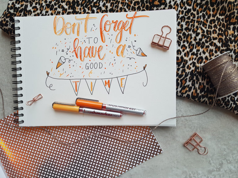 Lettering mit Verzierungen auf weißem Papier mit orangen Stiften und der Aufschrift "Don't forget to have a good time"